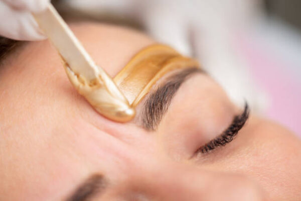 Applying Gold Colored Wax with Spatula on Woman's Face [object object] Why Choose Sassy Nails? waxing 600x400